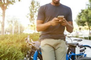 person leaning on bike while holding smartphone